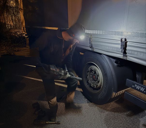 Mobile truck repair mechanic working on a heavy goods vehicle on the hard shoulder of a European motorway